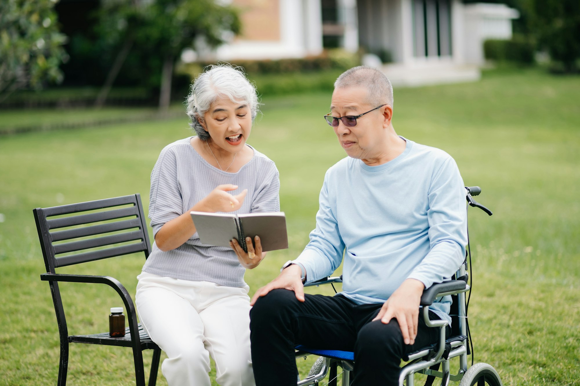 Asian Senior couple sitting in wheelchairs taking care of each other.